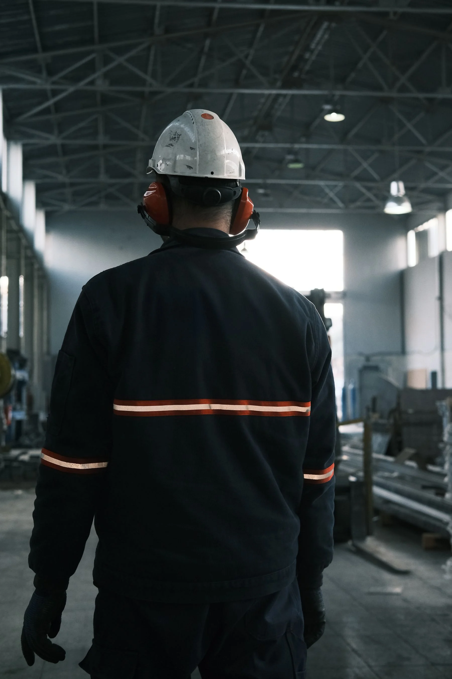 A worker wearing a hard hat and protective workwear in an industrial facility